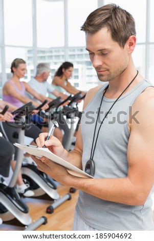 Portrait of a trainer with people working out at bike class in gym