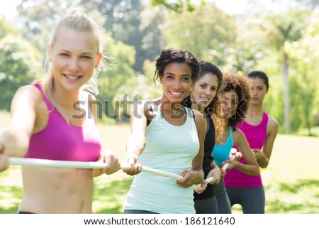 Happy women pulling a rope in tug of war at the park