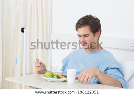 Young male patient eating meal in hospital ward