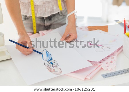 Closeup mid section of a female fashion designer working on her designs in the studio