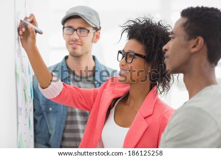 Group of artists in discussion in front of whiteboard at office