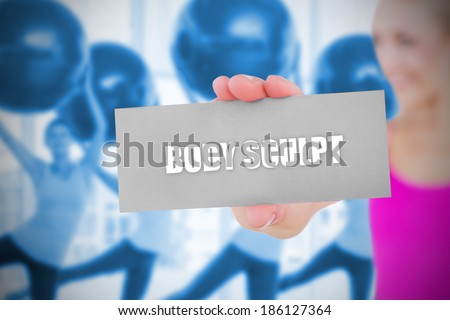 Fit blonde holding card saying body sculpt against fitness class in gym