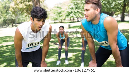 Young tired marathon runners standing in park