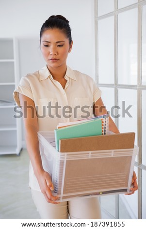 Fired businesswoman holding box of her things in the office