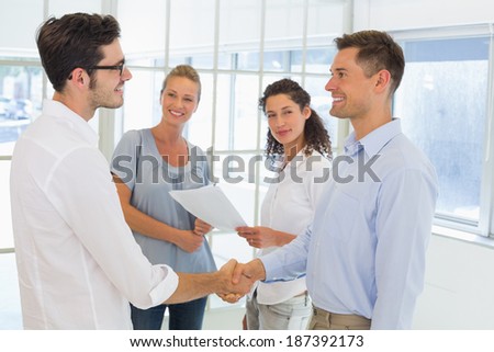 Casual businessmen shaking hands and smiling in the office