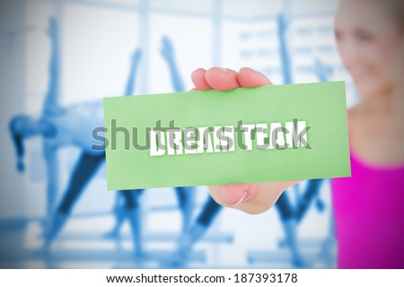 Fit blonde holding card saying dream team against fitness class in gym