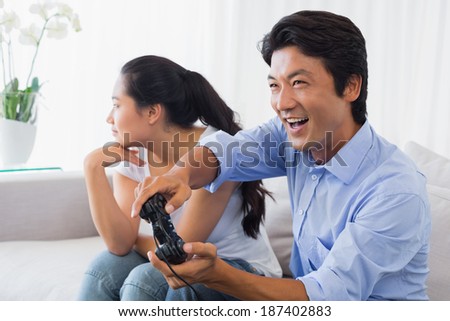 Woman being ignored by boyfriend playing video games at home in the living room
