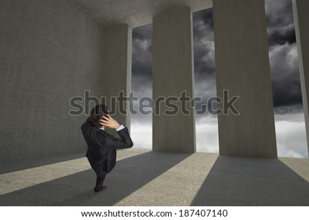 Stressed businessman with hands on head against light shining into dark room