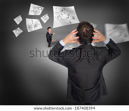 Stressed businessman with hands on head with tiny businessman against grey vignette