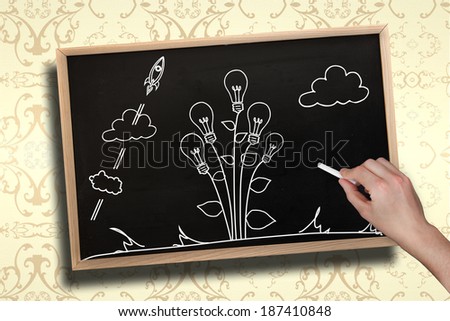 Composite image of hand drawing light bulb plant with chalk on chalkboard with wooden frame
