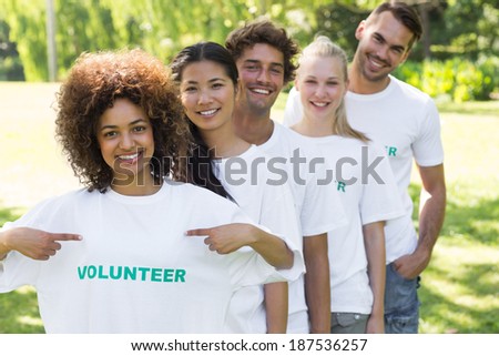 Portrait of environmentalist showing volunteer tshirt with friends standing in line behind