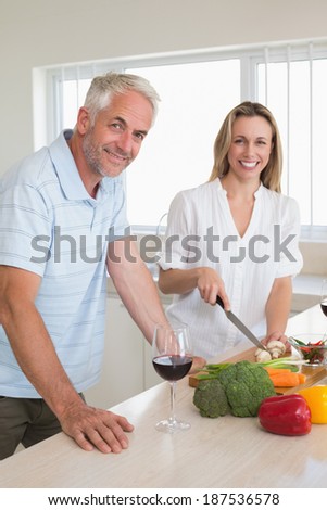 Cheerful couple making dinner together at home in the kitchen