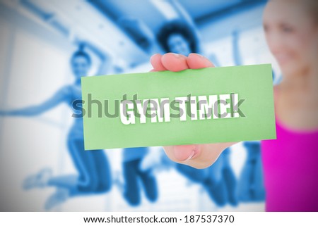 Fit blonde holding card saying gym time against class in gym