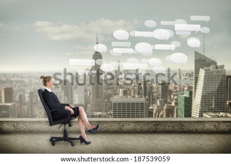Businesswoman sitting on swivel chair in black suit against balcony overlooking city