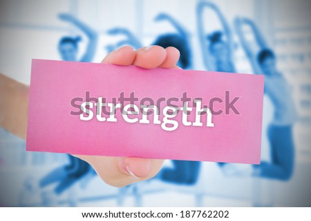 Woman holding pink card saying strength against class in gym