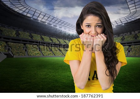 Nervous football fan in brasil tshirt in a large football stadium with fans in yellow