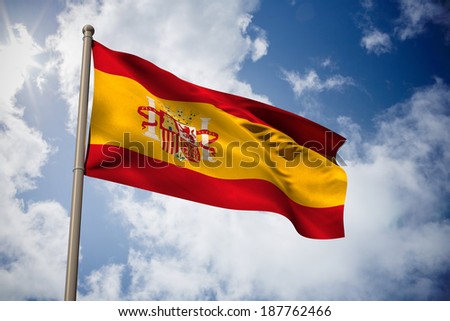 Spain national flag against bright blue sky with clouds