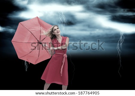 Elegant blonde holding umbrella against stormy dark sky with lightning bolts