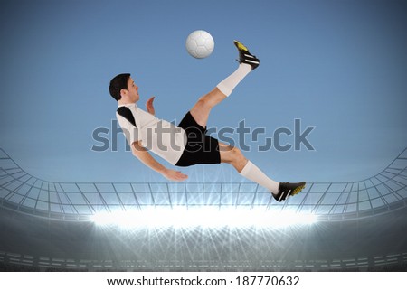 Football player in white kicking against large football stadium with spotlights under grey sky