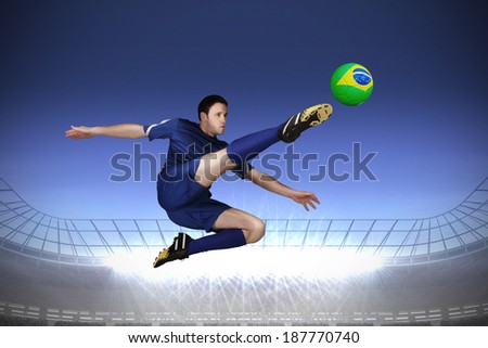 Football player in blue kicking against large football stadium with spotlights under dark blue sky