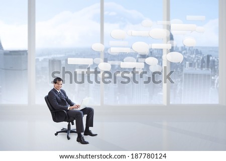 Young businessman sitting working with a laptop against bright white room with windows