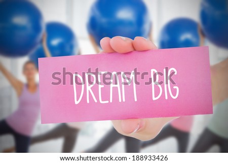 Woman holding card saying dream big against fitness class in gym