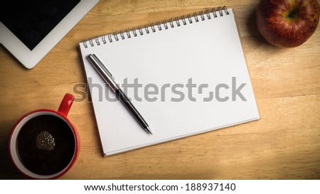 Overhead of notepad and pen on a cluttered desk