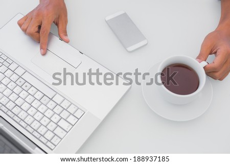 Man having coffee and using laptop outside on a balcony