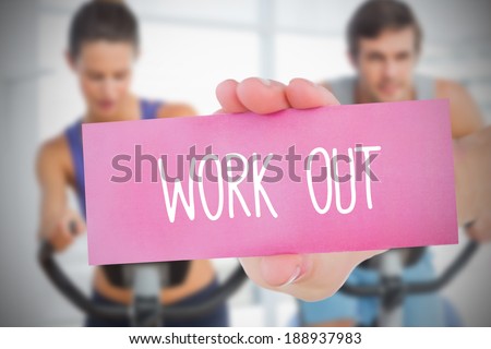 Woman holding pink card saying work out against fitness class in gym