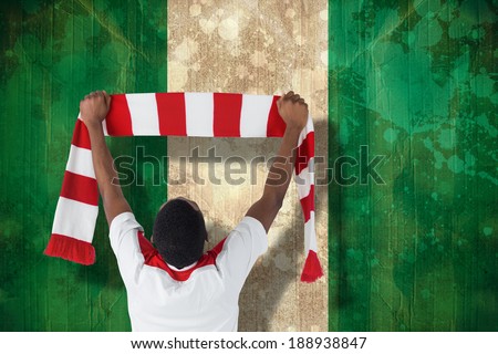 Happy football fan waving scarf against nigeria flag in grunge effect