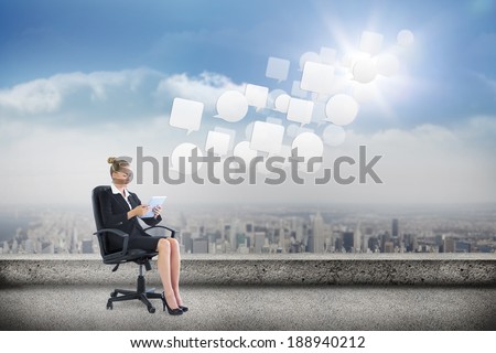Businesswoman sitting on swivel chair with tablet against balcony overlooking city