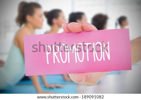 Woman holding pink card saying promotion against yoga class in gym