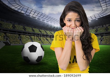 Nervous football fan in brasil tshirt against large football stadium with fans in yellow