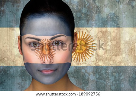 Composite image of beautiful football fan in face paint against argentina flag in grunge effect