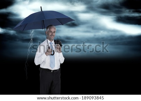 Happy businessman holding umbrella against stormy dark sky with lightning bolt