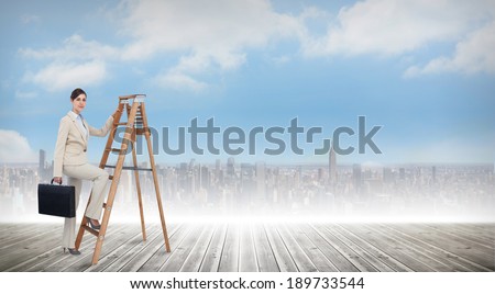 Businesswoman climbing career ladder with briefcase and looking at camera against cityscape on the horizon
