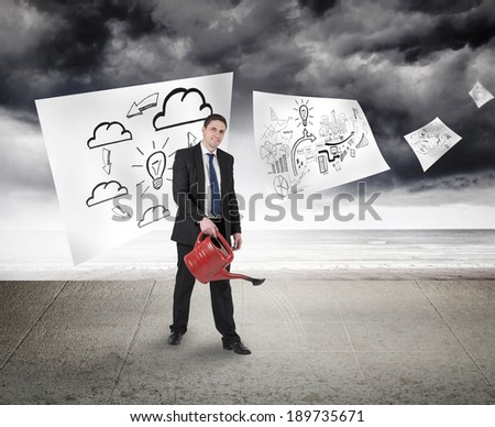 Businessman holding red watering can against sheets with graphic over sky on wall