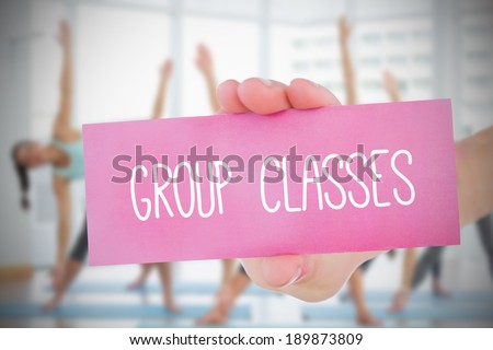 Woman holding pink card saying group classes against fitness class in gym