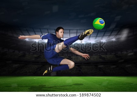 Football player in blue kicking against large football stadium with fans in yellow