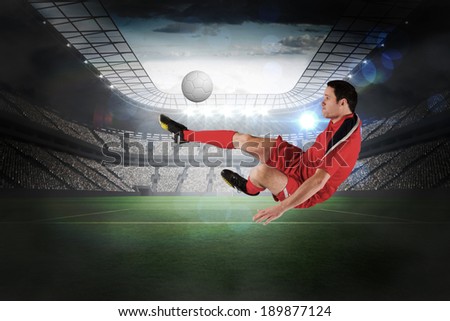 Football player in red kicking in a large football stadium with lights