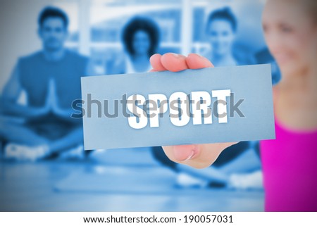 Fit blonde holding card saying sport against yoga class in gym