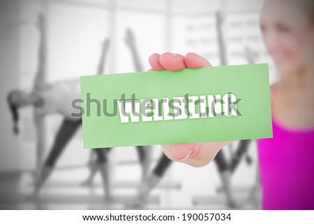 Fit blonde holding card saying wellbeing against fitness class in gym
