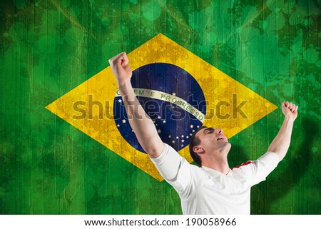 Excited football fan cheering against brazil flag in grunge effect