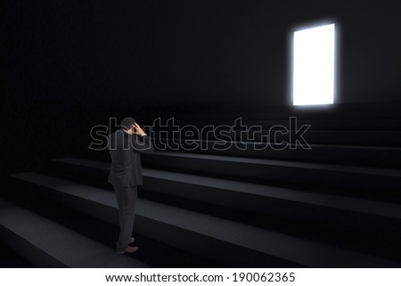 Stressed businessman with hands on head against steps leading to light in the darkness