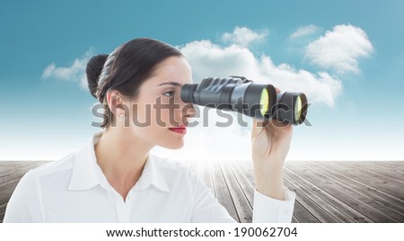 Business woman looking through binoculars against cloudy sky background