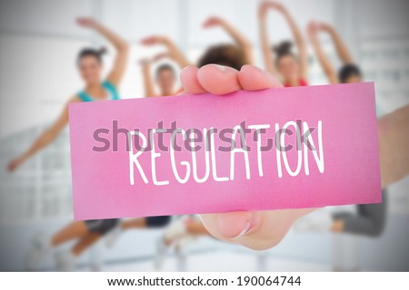Woman holding pink card saying regulation against fitness class in gym