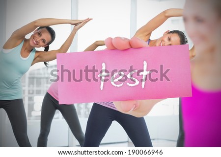 Fit blonde holding card saying test against fitness class in gym