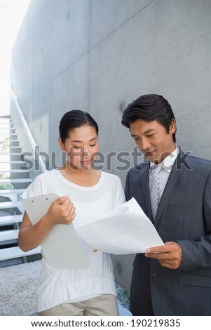 Estate agent showing lease to customer and smiling outside a house