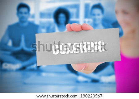 Fit blonde holding card saying coaching against yoga class in gym