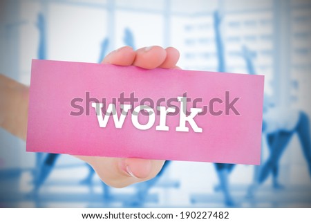 Woman holding pink card saying work against fitness class in gym